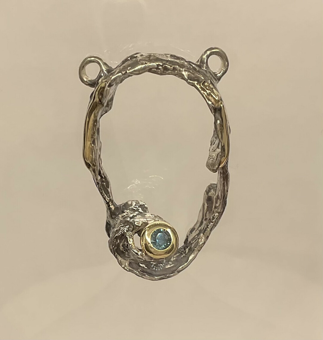 Metalsmith Liz created a Bird’s Nest with a Robin’s Egg Blue Sapphire for the March 2022 show. This Birch Bark pendant is composed of sterling silver, 14K yellow gold and has a genuine round sapphire. 